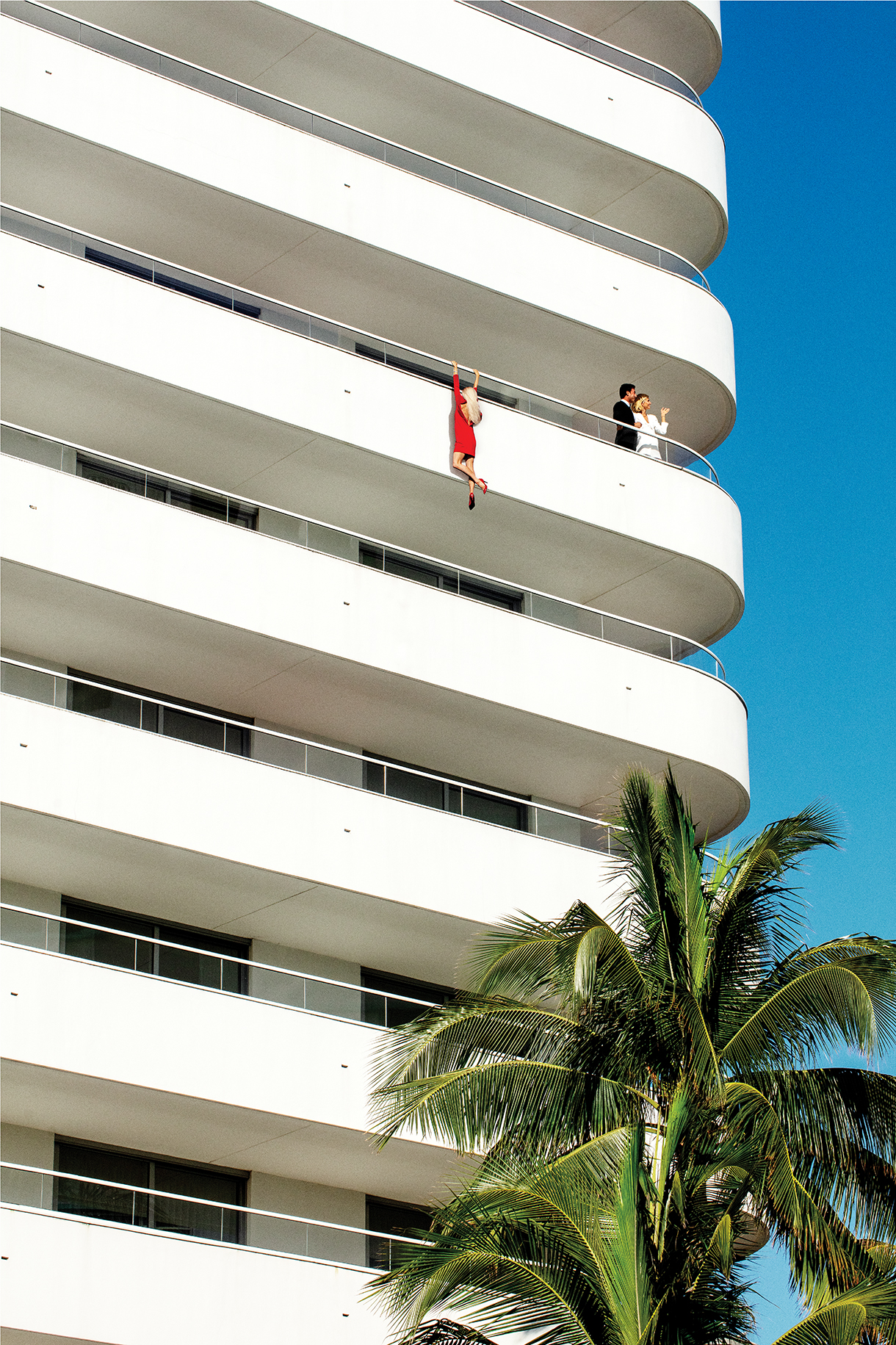 Woman in red dress hanging from a Miami skyrise balcony